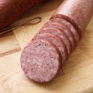 A bunch of sausage sitting on top of a wooden board.